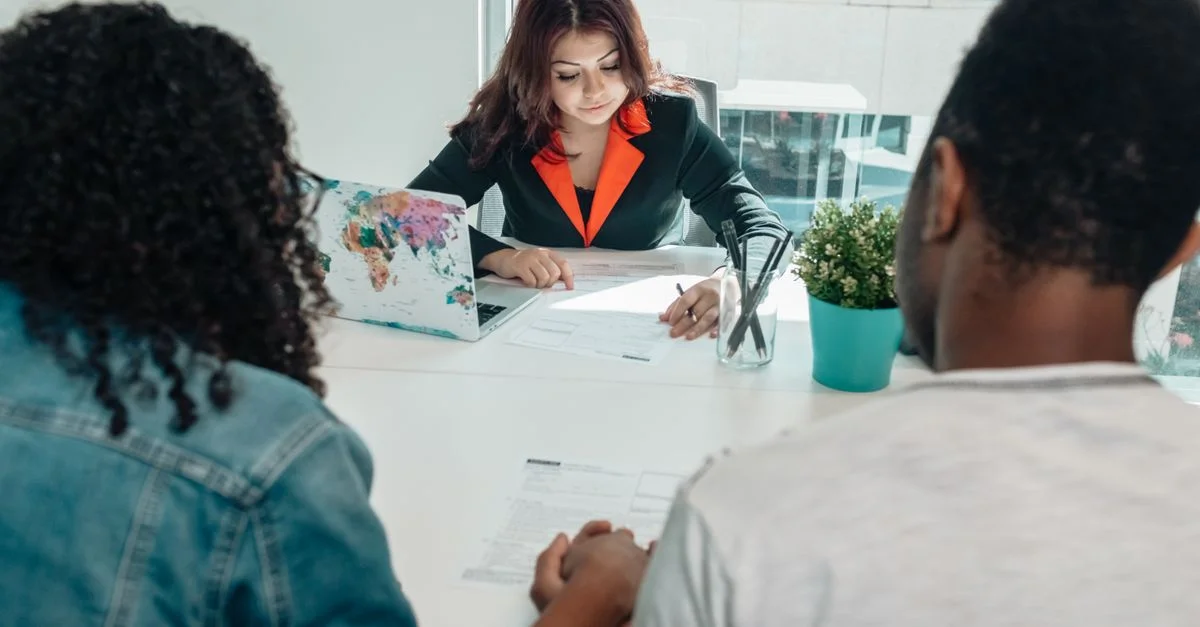 Un couple discutant de documents juridiques avec un avocat dans un environnement de bureau moderne.