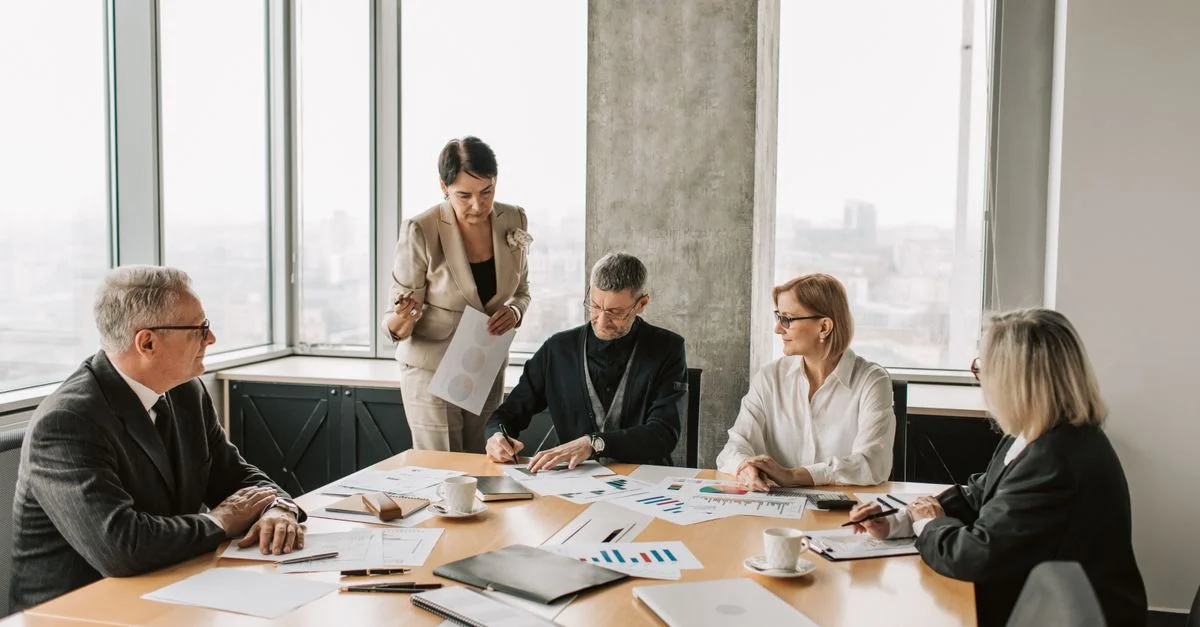 Des professionnels discutant de documents lors d'une réunion d'affaires dans un bureau moderne.