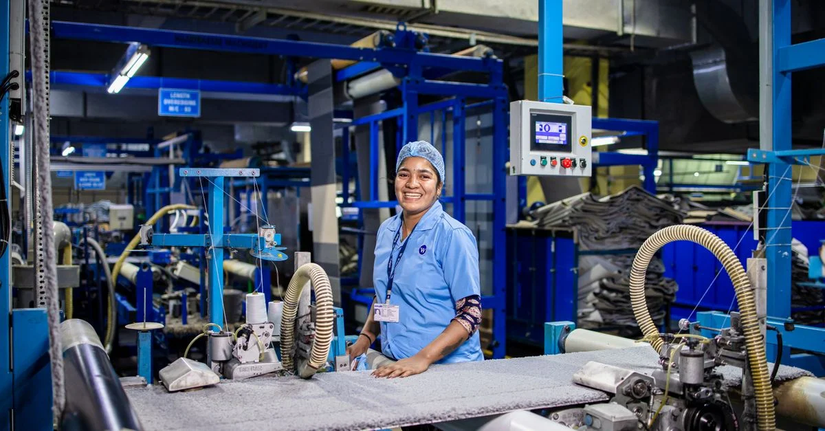 Ouvrier textile heureux utilisant une machine dans un environnement d'usine moderne.