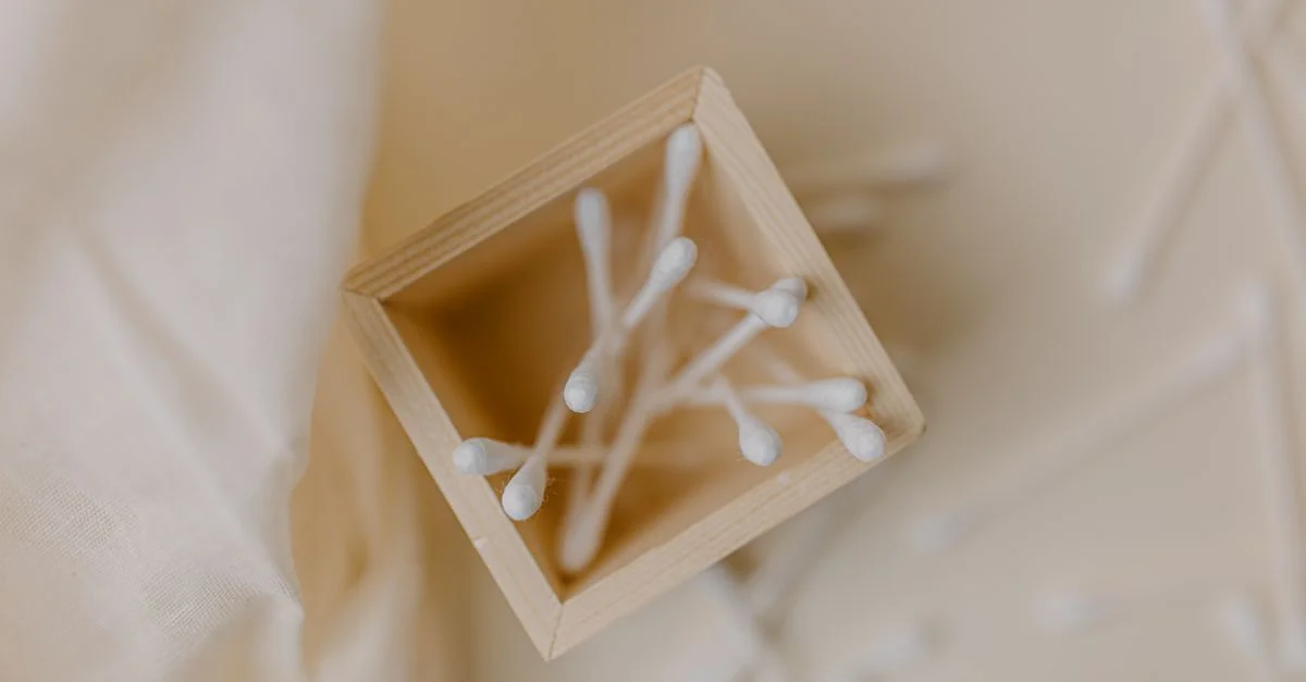 Vue du dessus des coton-tiges dans une boîte en bois avec un style neutre et minimaliste.