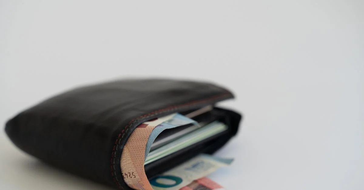 Gros plan sur un portefeuille en cuir rempli de billets en euros sur un fond blanc, parfait pour les thèmes financiers et de mode de vie.