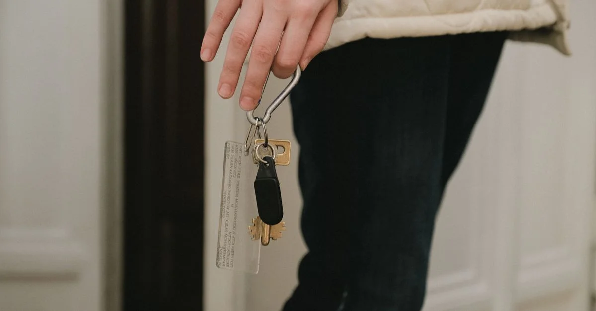 Une photo en gros plan d'une main adulte tenant un trousseau de clés de maison à l'intérieur, suggérant la sécurité et l'accès au domicile.