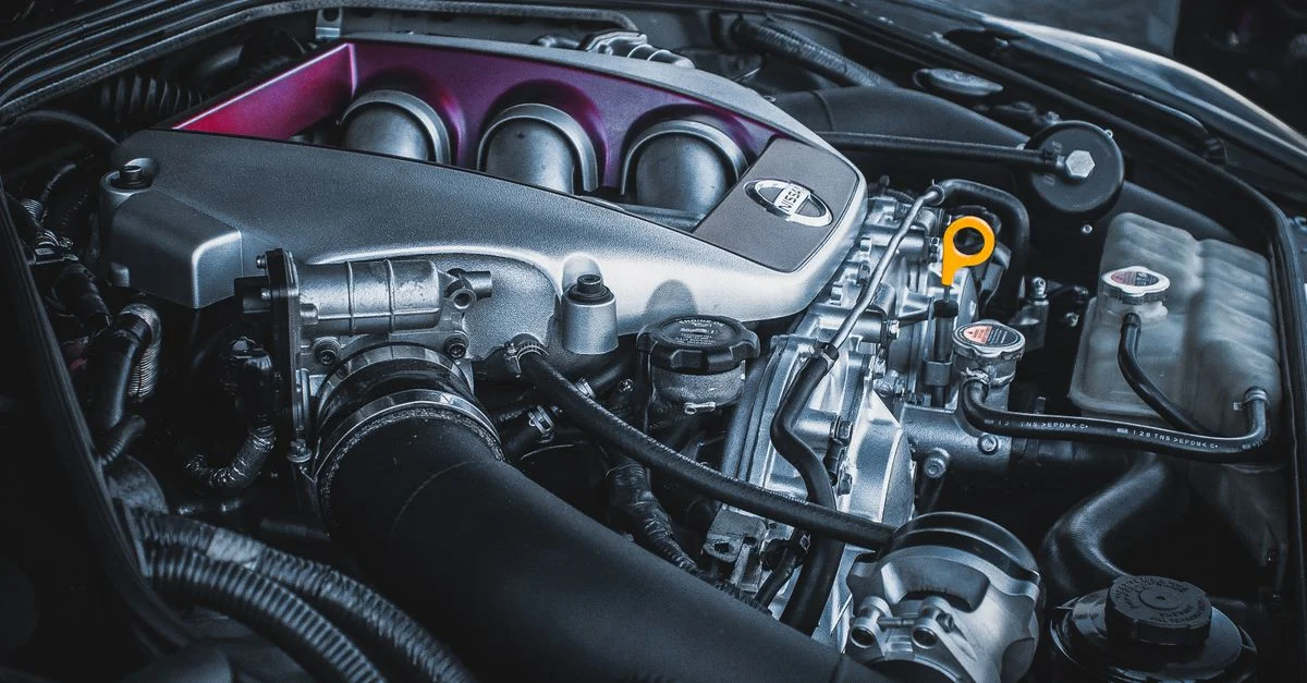 Prise de vue détaillée du compartiment moteur d'une Nissan, mettant en évidence des pièces et composants complexes.