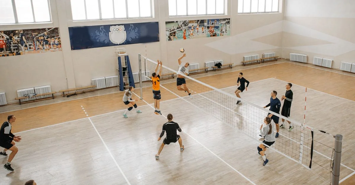 Match de volleyball compétitif avec des joueurs qui sautent et smashtent le ballon à l'intérieur.