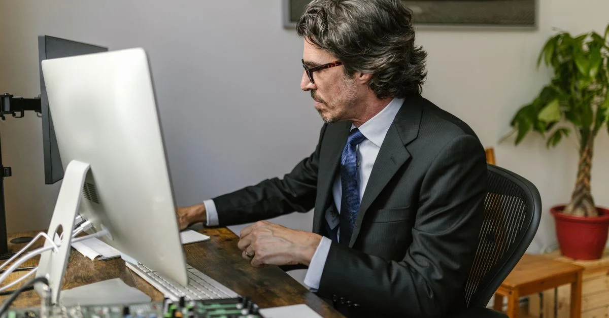 Professionnel en affaires en costume travaillant sur un ordinateur dans un cadre de bureau moderne.