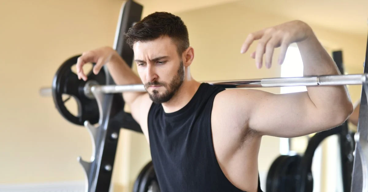 Homme effectuant un exercice de musculation, montrant force et concentration dans un environnement de gym.