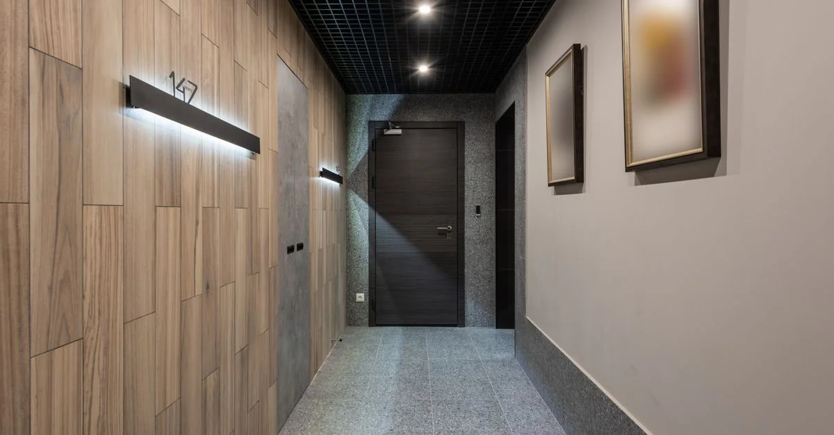 Un couloir d'hôtel élégant et contemporain avec des lambris en bois et un éclairage d'ambiance, créant une ambiance intérieure luxueuse.